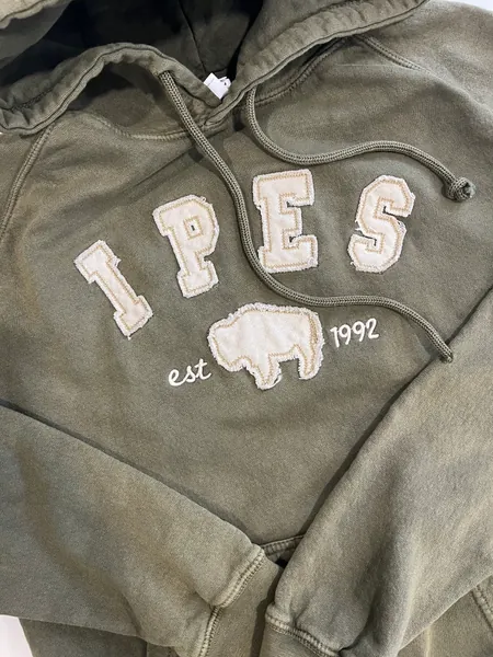 Olive hoodie with IPES letters and a bison in raw-edge appliqué, and est 1992 stitched in white